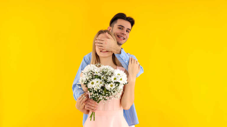 Cute couple with bouquet on yellow background