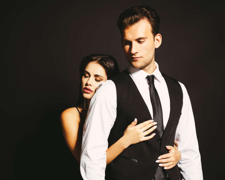 Young brunette woman with closed eyes embracing elegant man isol
