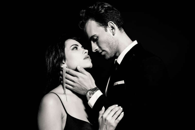 Young man in elegant suit seducing stylish brunette woman isolat