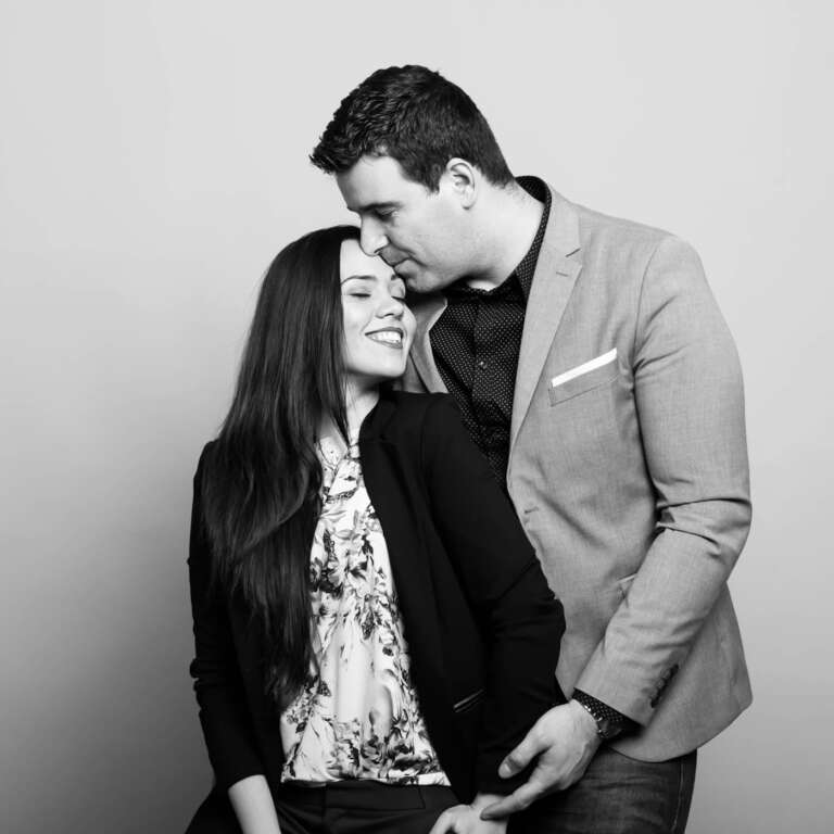 Husband kissing his wife forehead over yellow background.